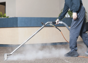 A technician performing hot water extraction on commercial carpet