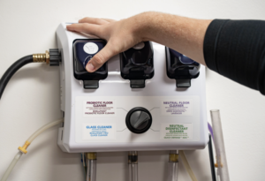 An automated chemical dilution dispenser mounted in a commercial janitorial closet